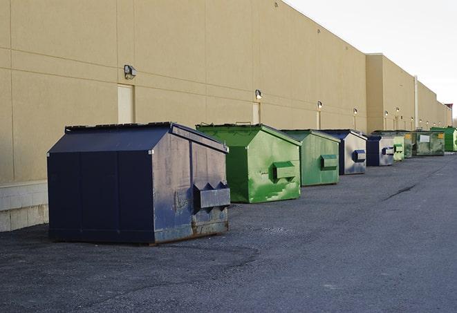 a row of yellow and blue dumpsters at a construction site in Congers, NY